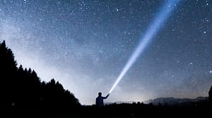 Photo of Person with a Flashlight Shining into the Starry Sky