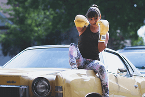 Woman Boxer Sitting on a Car Smiling